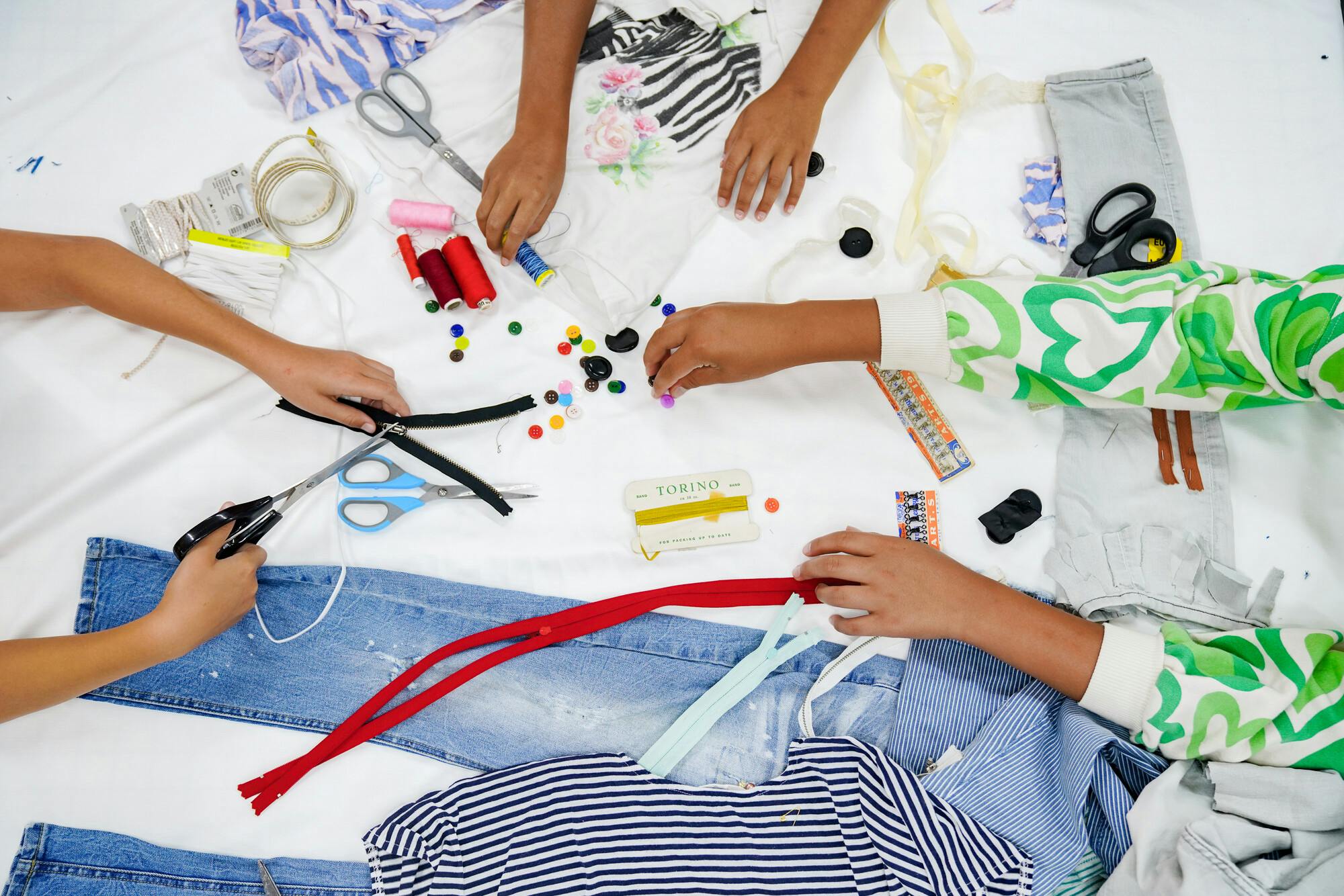 Kinderhanden, oude jeansbroeken en materialen