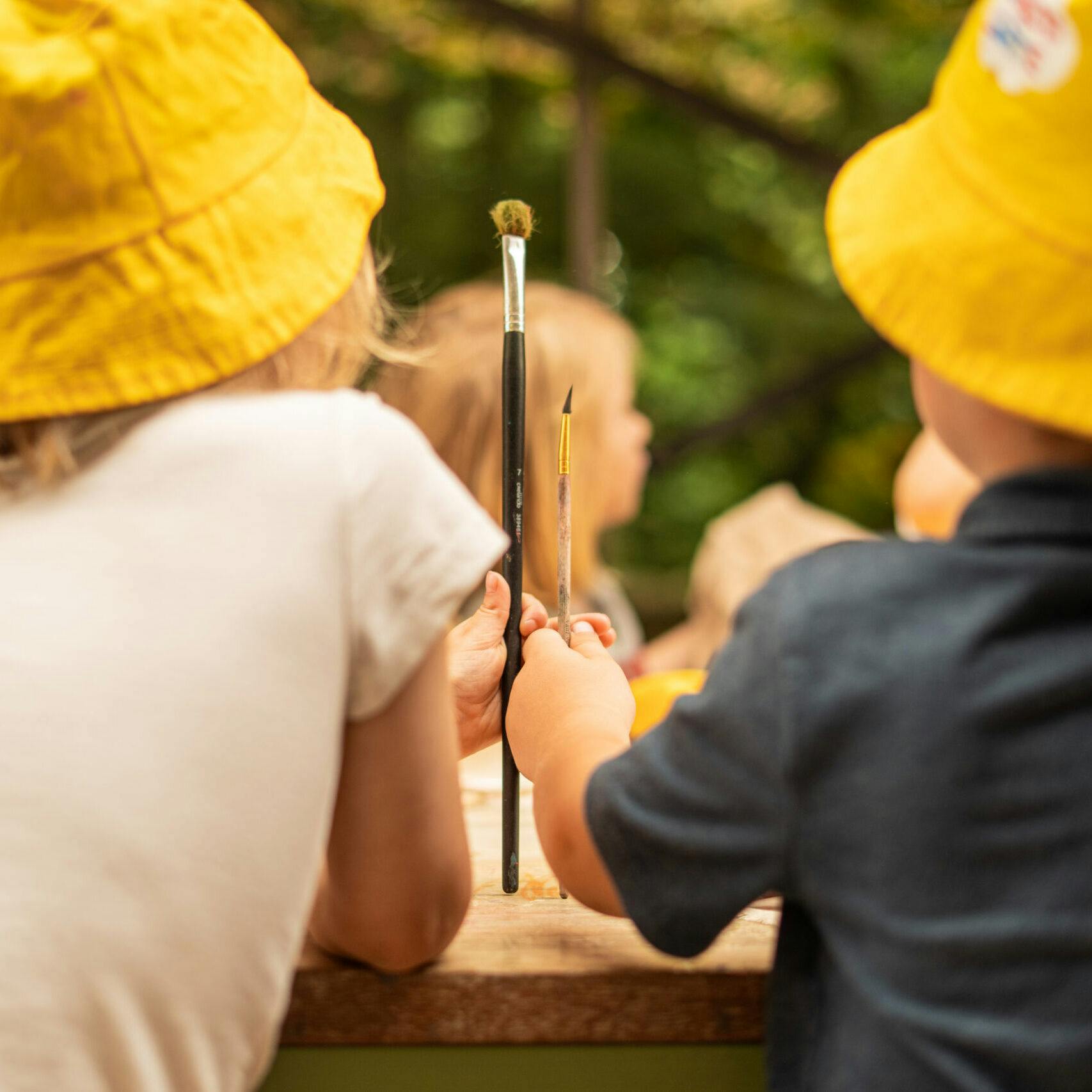 Twee kindjes met een penseel en geel hoedje
