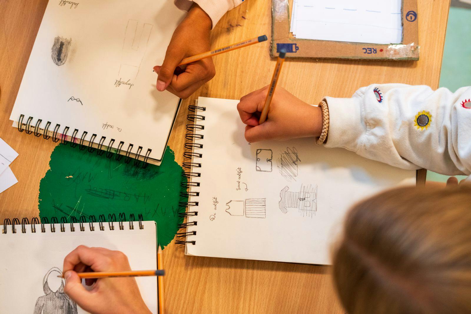 Kinderen die kleren ontwerpen in een schetsboek